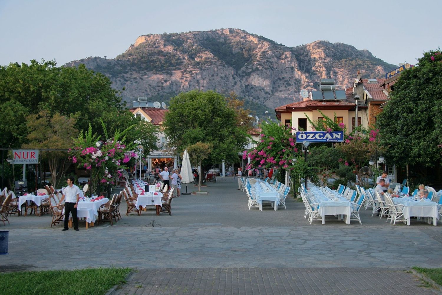Riverside restaurant tables in Dalyan town beneath the cliffs